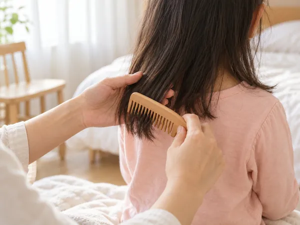 아침 햇살 아래 피치핑크 옷을 입은 아이의 머리끝을 나무 빗으로 빗는 손